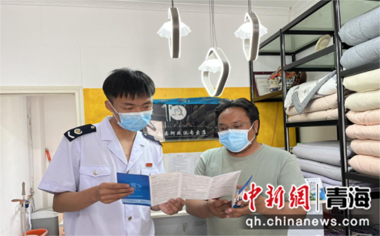 图为工作人员走访商户宣传相关政策。